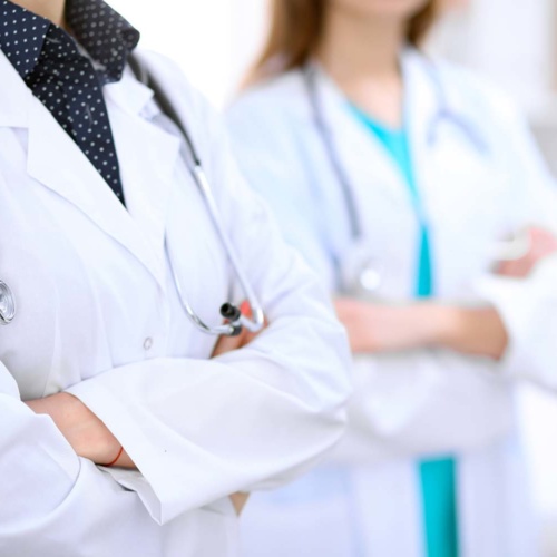 Unknown female doctor standing in a hospital with her colleague in the background Close up of unknown female doctor standing in a hospital with her colleague in the background