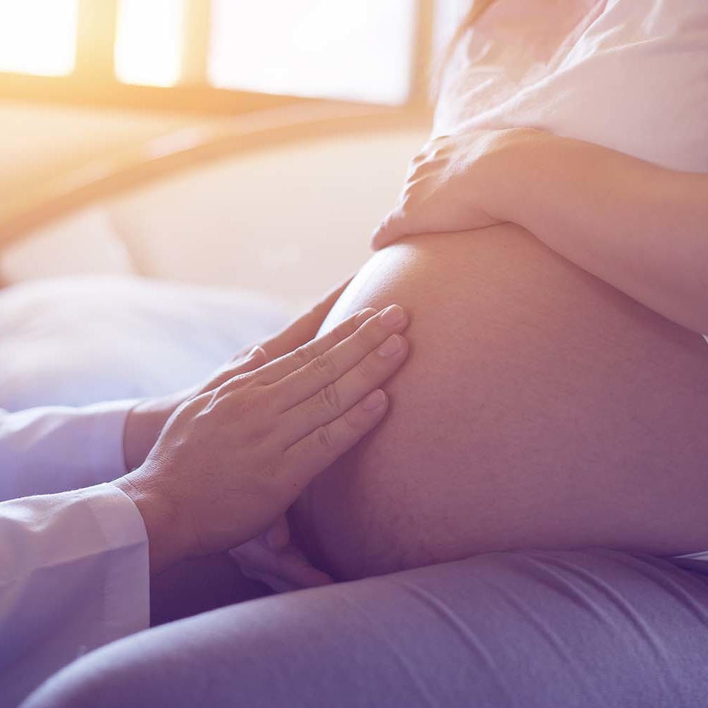 doctor using hand and stethoscope white examining pregnant woman OB/GYN examining patient's pregnancy with hands