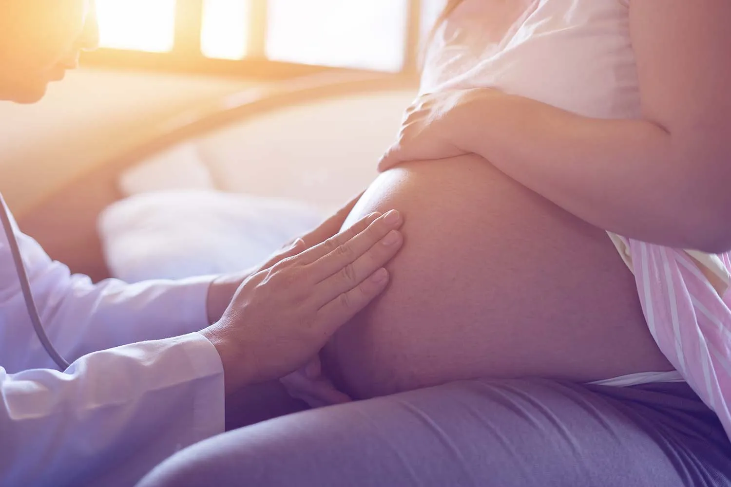 doctor using hand and stethoscope white examining pregnant woman OB/GYN examining patient's pregnancy with hands