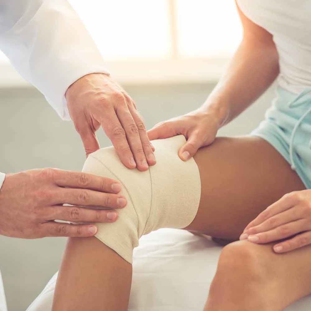 Doctor and patient orthopedic surgeon bandaging woman's knee