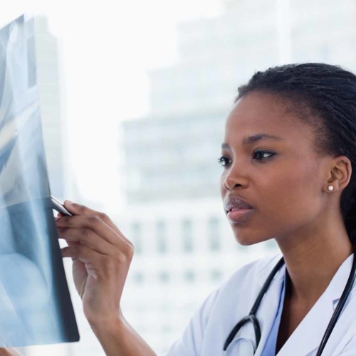 Focused female doctor looking at a set of X-rays Focused female doctor looking at a set of X-rays in her office