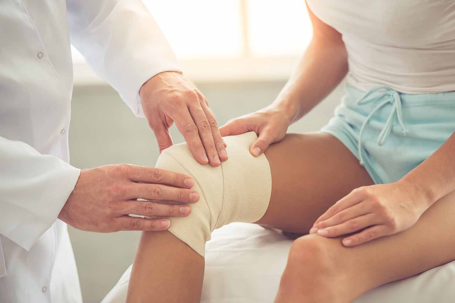 orthopedic surgeon bandaging woman's knee