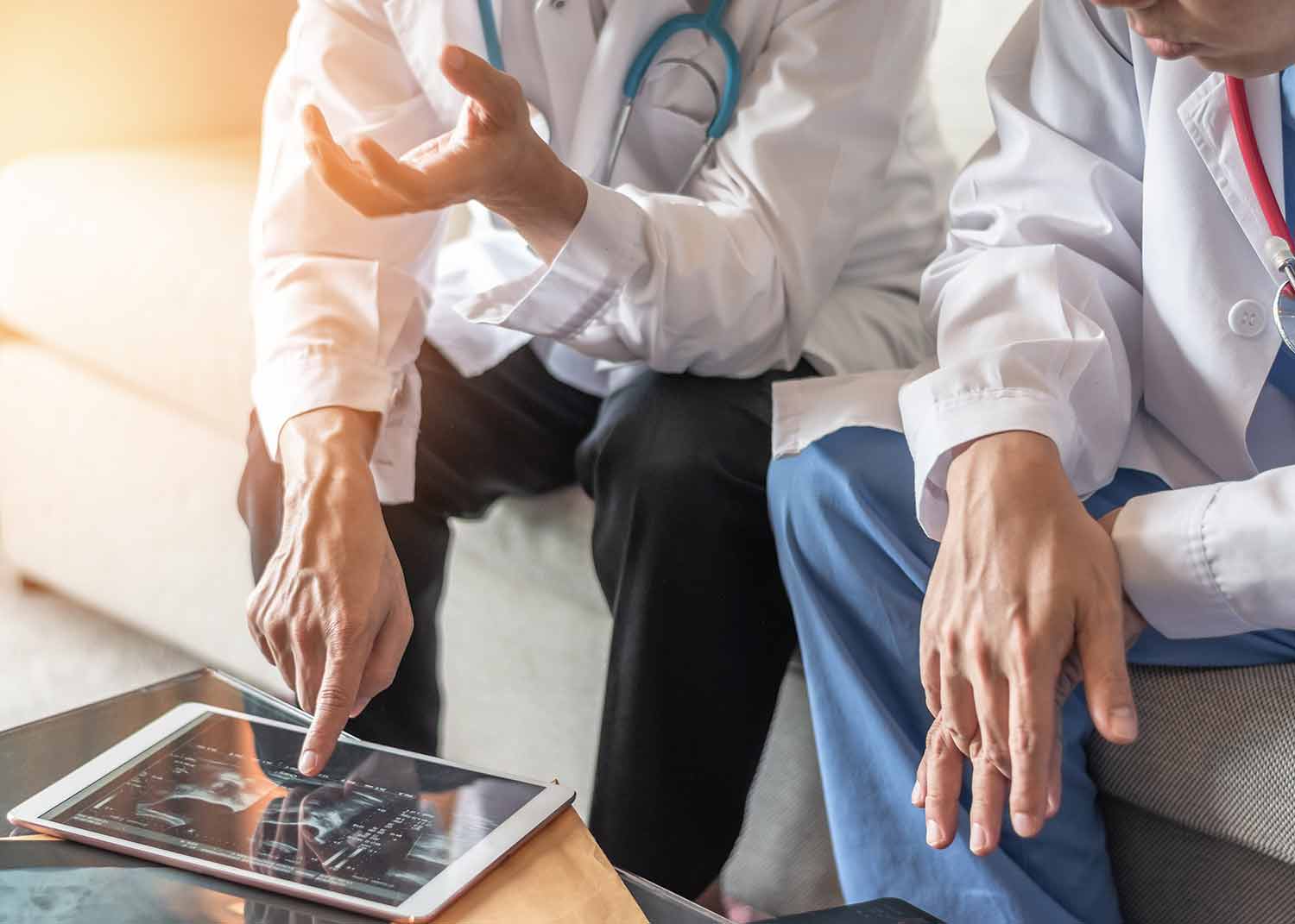 Two Male Florida Orthopedic Surgeons Review Patient Records On A Tablet