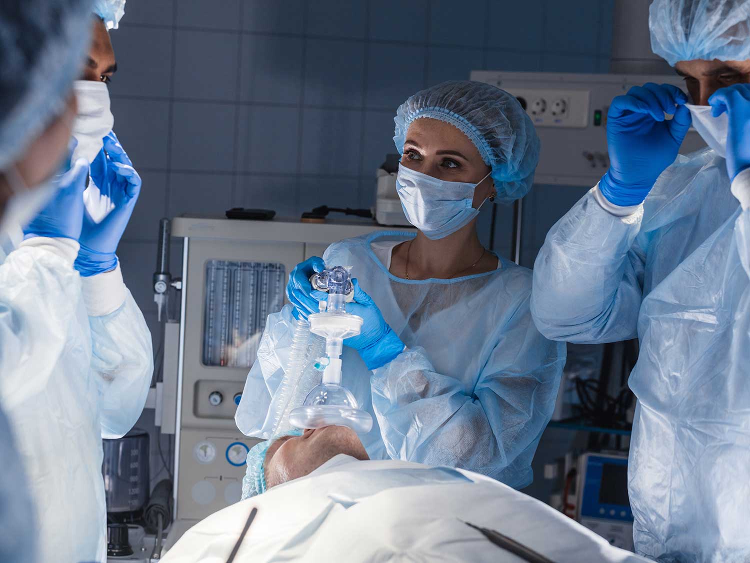A Group Of Anesthesiologists Surround A Patient Wearing A Mask