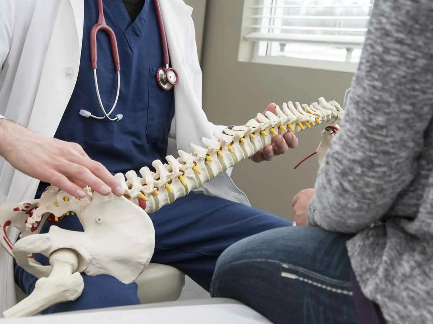 A Florida Orthopedic Surgeon With Malpractice Insurance Explaining A Model Of A Spine To A Patient