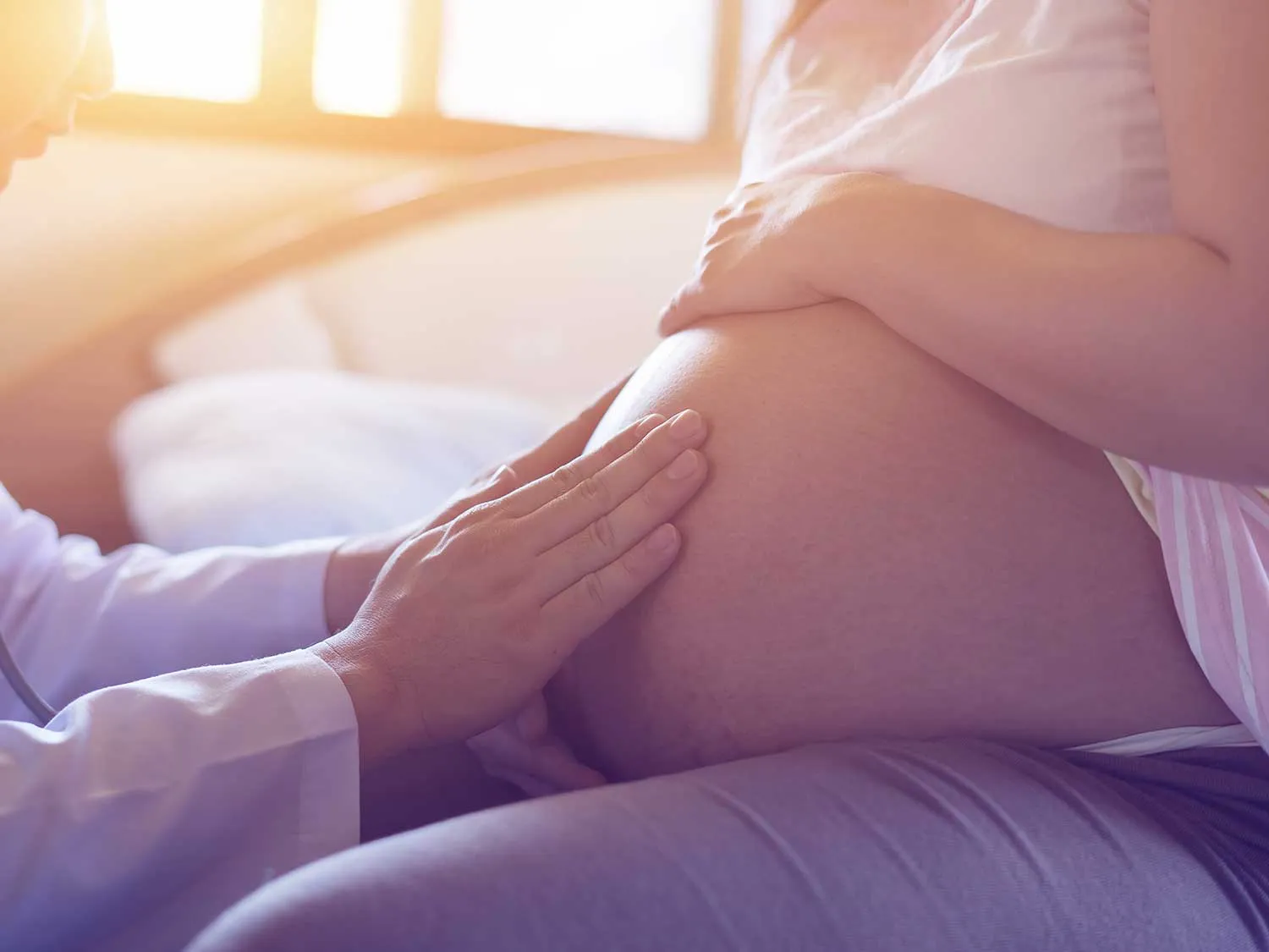 An OBGYN With Medical Liability Coverage Examining The Stomach Of A Pregnant Patient