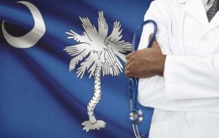 A Doctor With A Medical Malpractice Insurance Policy From MEDPLI Standing In Front Of The South Carolina Flag