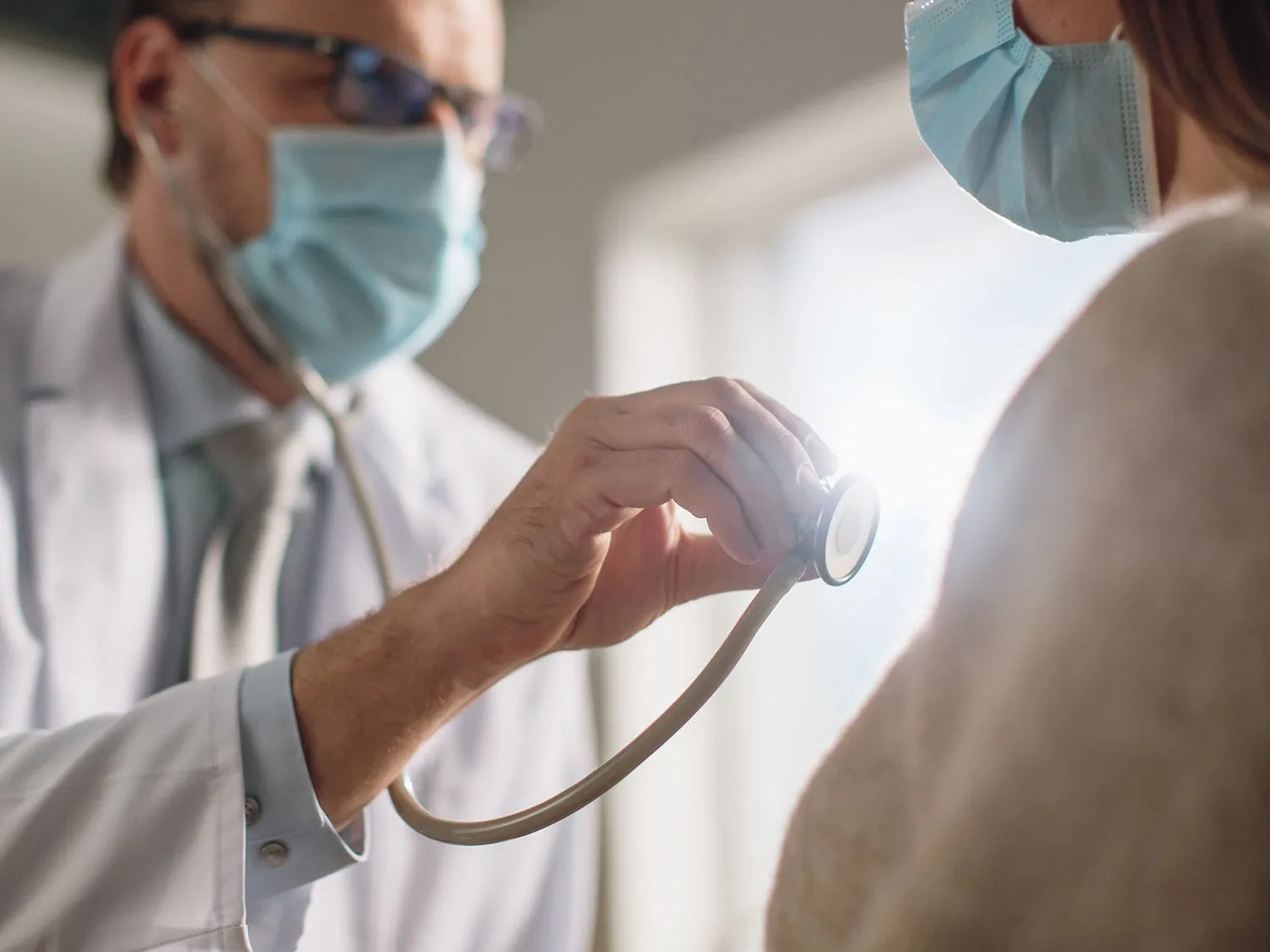 A Male cardiologist With Medical Malpractice Insurance Using A Stethoscope To Listen To A Female Patient's Heart