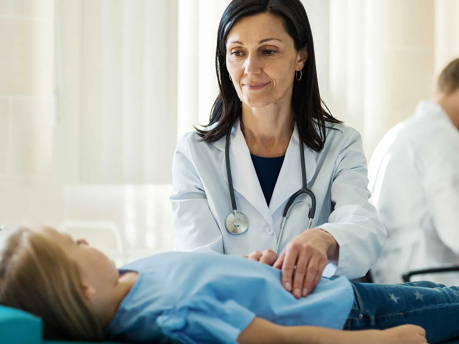 A Female Gastroenterologist With Medical Malpractice Insurance From MEDPLI Examines The Stomach Of A Young Girl