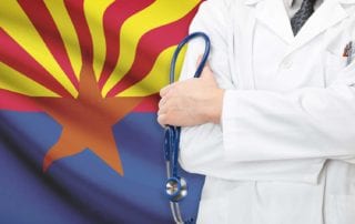 Doctor Seeking Medical Malpractice Insurance Standing With Arms Folded In Front Of An Arizona Flag