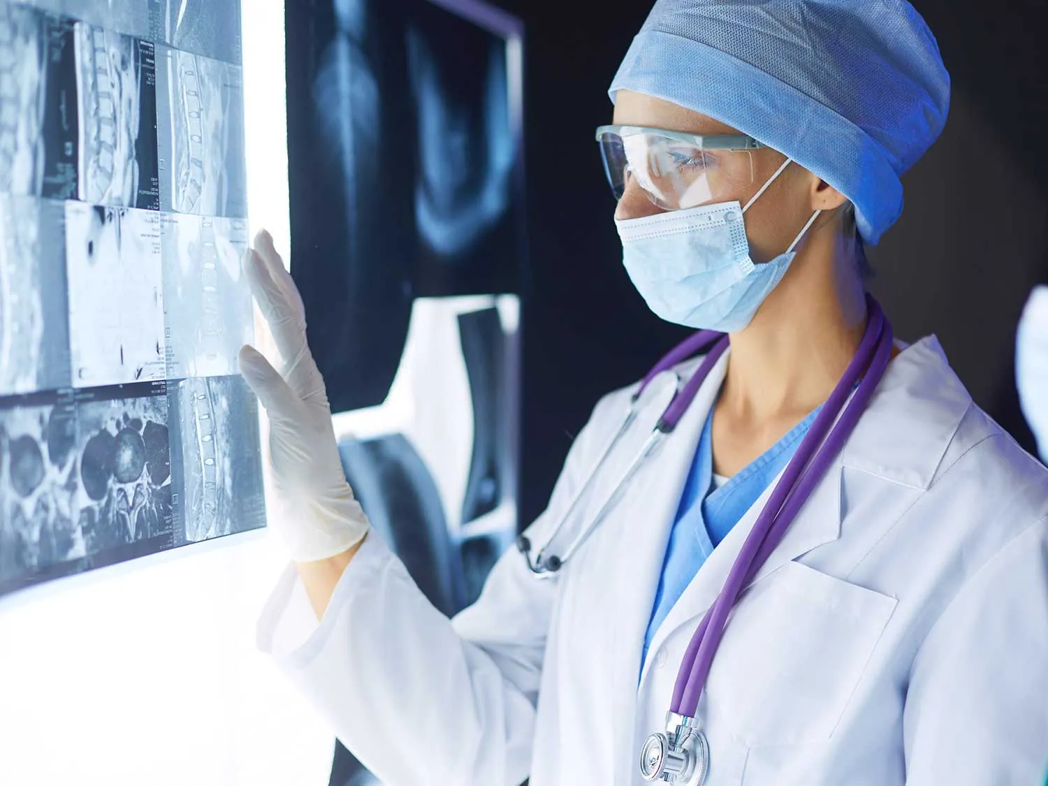 A Masked Female Radiologist With Tailored Medical Malpractice Insurance Examining A Set Of XRays