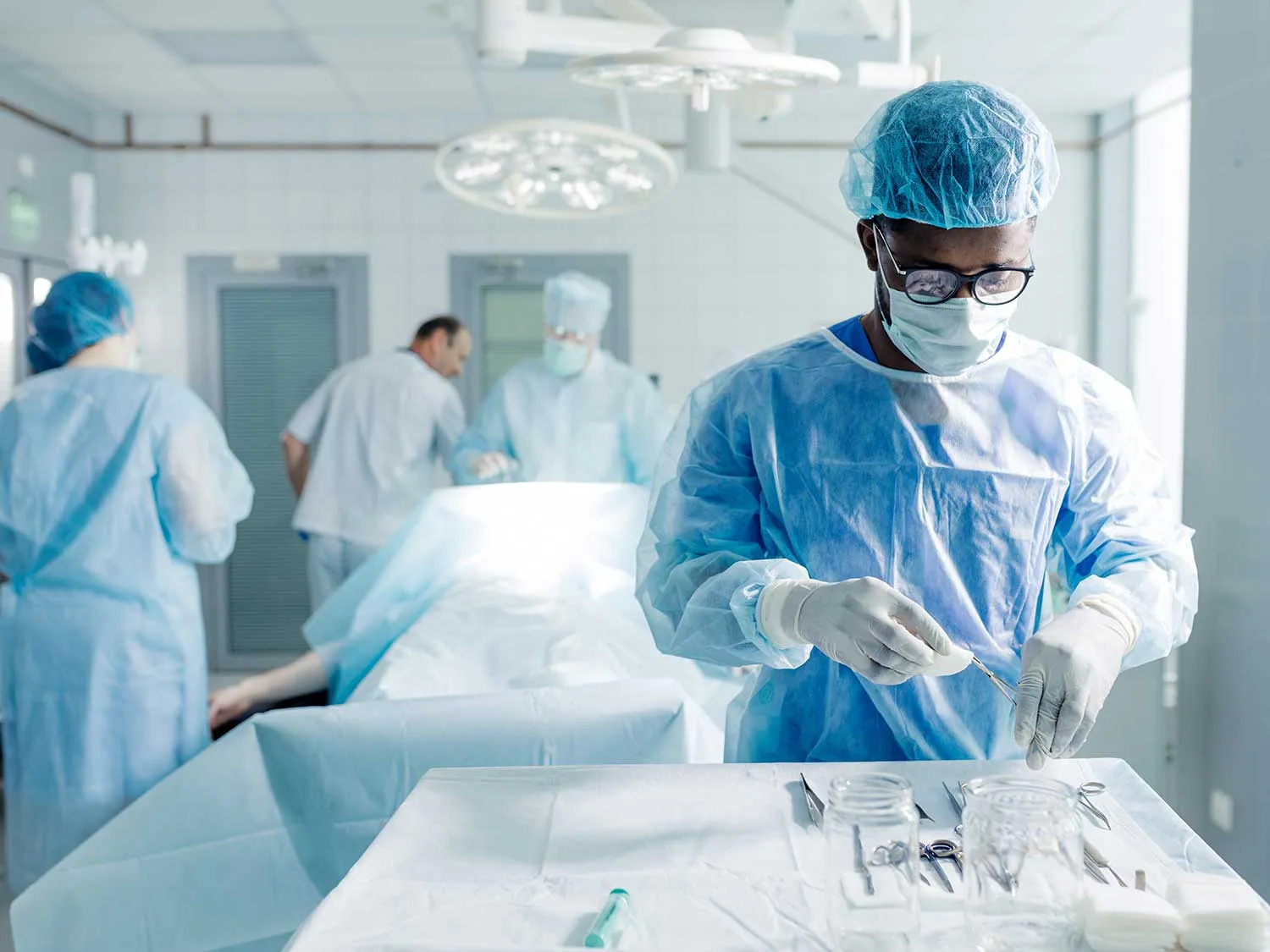 A General Surgeon Covered By Comprehensive Medical Malpractice Insurance Preparing Instruments For Surgery
