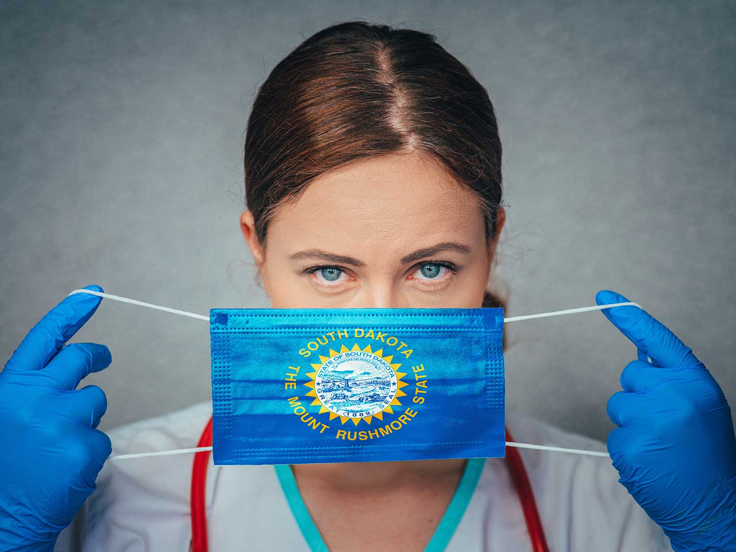 A Female Doctor From South Dakota With Medical Malpractice Insurance Putting On A State Flag Surgical Mask