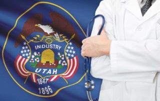 A Utah Physician With Medical Malpractice Insurance Holding a Stethoscope In Front Of A Utah State Flag