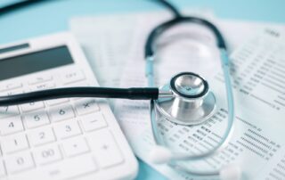 Stethoscope laying near calculator and insurance forms for medical malpractice