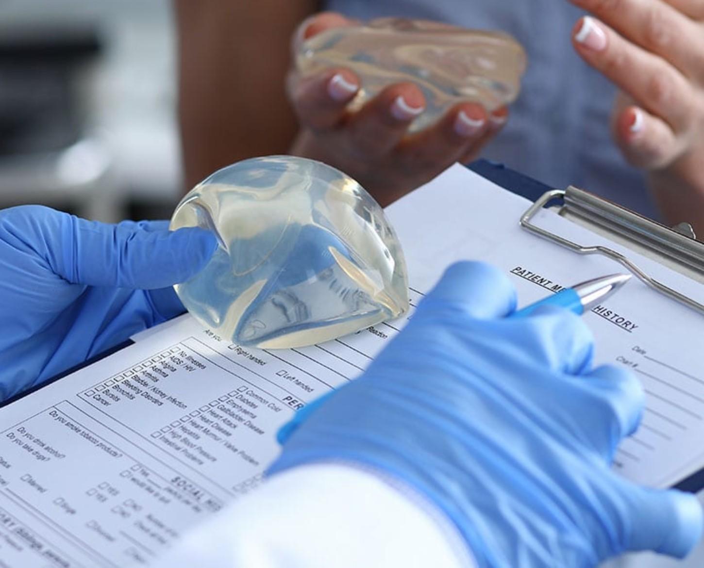 Image of a platic surgeon, analyzing documents and preparing for a breast implant surgery.